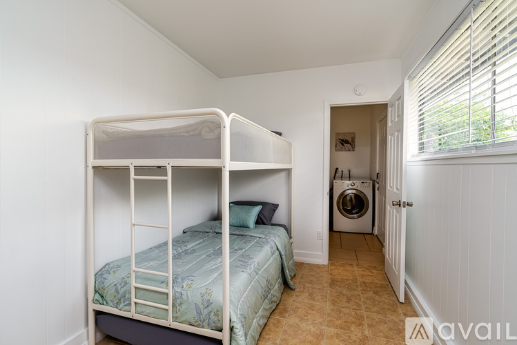 A bedroom with a bunk bed and a washing machine in the hallway.