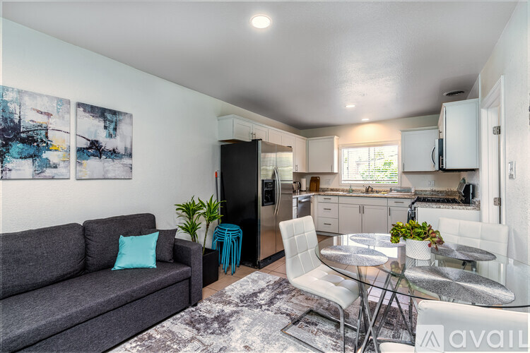 A modern living room with a grey couch and a glass dining table.