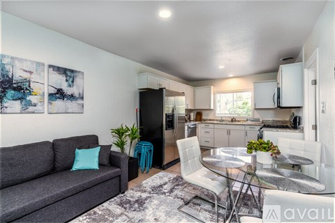 A modern living room with a grey couch and a glass dining table.