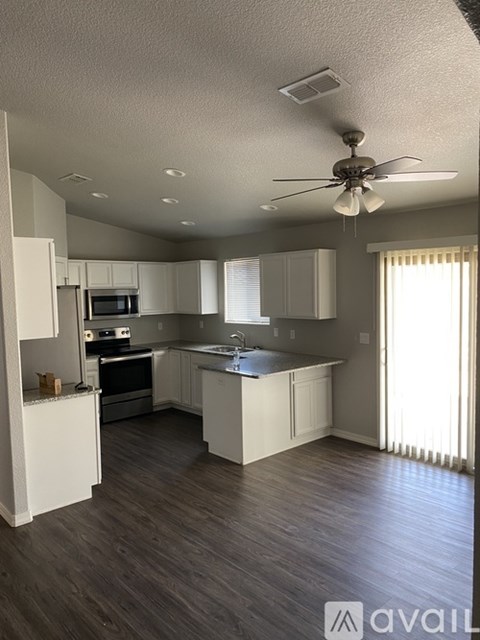A spacious kitchen with a ceiling fan and wooden flooring.