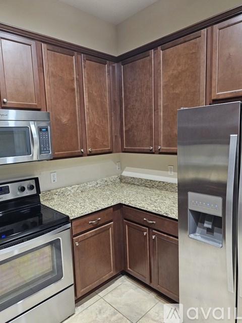 A kitchen with wooden cabinets and a stainless steel refrigerator.