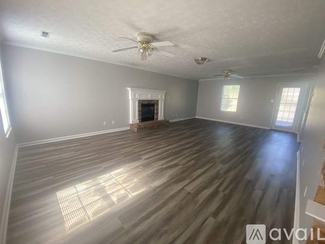 A spacious room with wooden flooring and a ceiling fan.