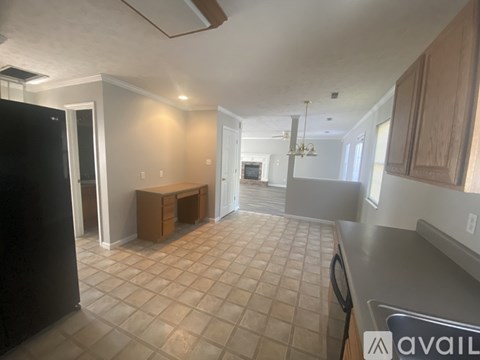 A kitchen with a black refrigerator and a tiled floor.