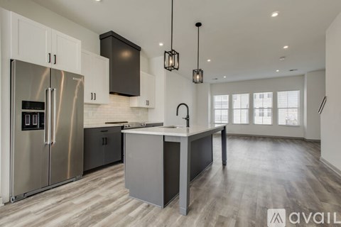 A modern kitchen with a stainless steel refrigerator and wooden flooring.