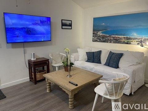 A living room with a television, a sofa, a coffee table, and a painting on the wall.