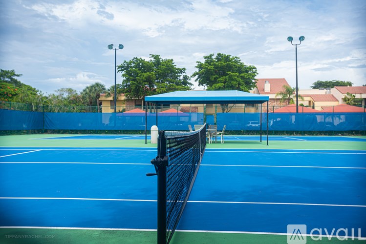 A tennis court with a blue surface and a black fence.
