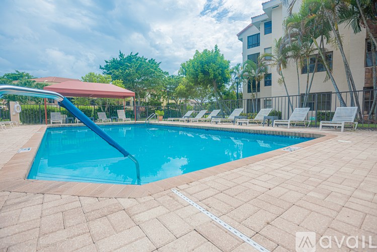 A swimming pool with a red canopy and lounge chairs.