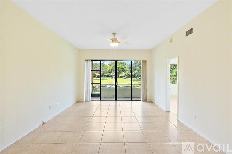A spacious room with a ceiling fan and sliding glass doors leading to a garden.