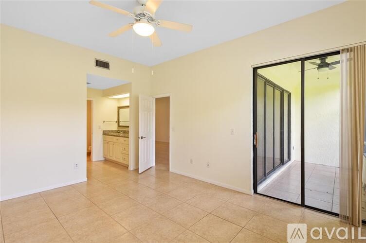 A room with a ceiling fan and sliding glass doors.