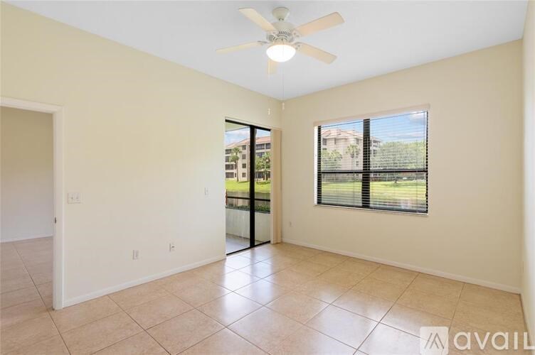 A room with a ceiling fan and sliding glass doors leading to a balcony.