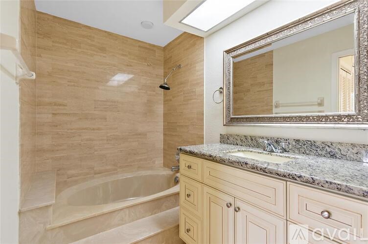 A bathroom with a tub, sink, and mirror.