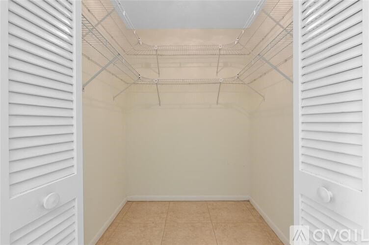 A room with white walls and a tiled floor with a ceiling of exposed pipes.