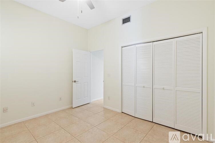 A room with a white door and a white closet with a fan on the ceiling.