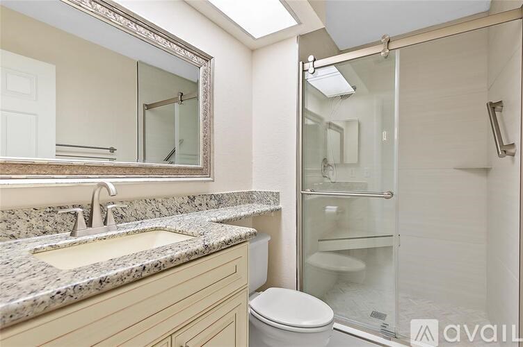 A bathroom with a marble countertop and a walk-in shower.