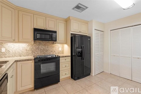 A kitchen with black appliances and wooden cabinets.