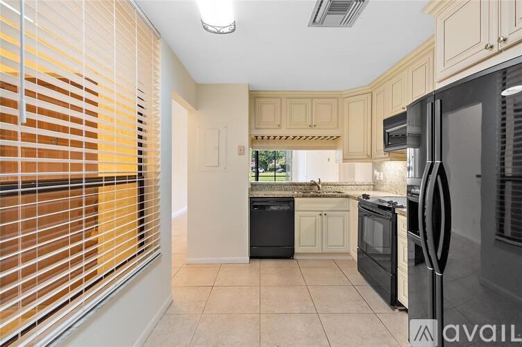 A kitchen with a black fridge and white cabinets.