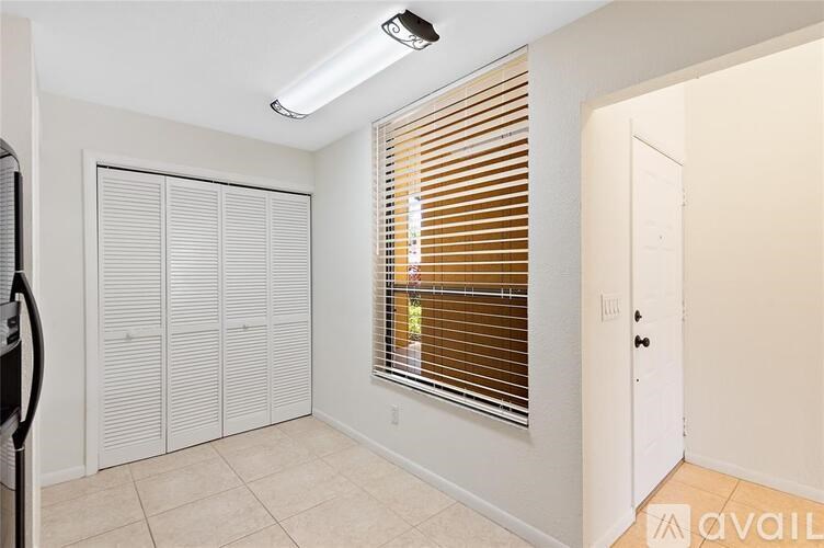 A room with a window covered in blinds and a white door.