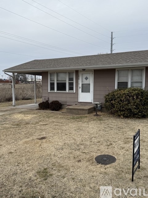 A house with a brown roof and a white door is surrounded by a grassy area.