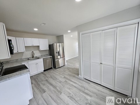 A kitchen with white cabinets and a grey floor.