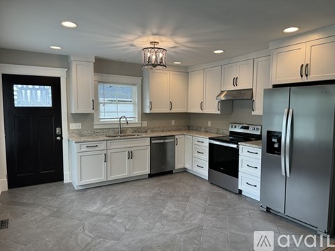 A kitchen with white cabinets and a black door.