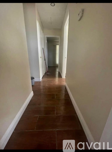 A long hallway with a brown floor and white walls.