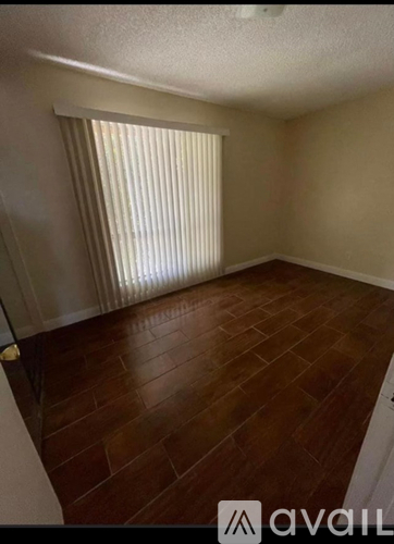 A room with wooden flooring and a window with blinds.