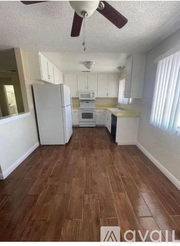 A kitchen with white appliances and wooden floors.