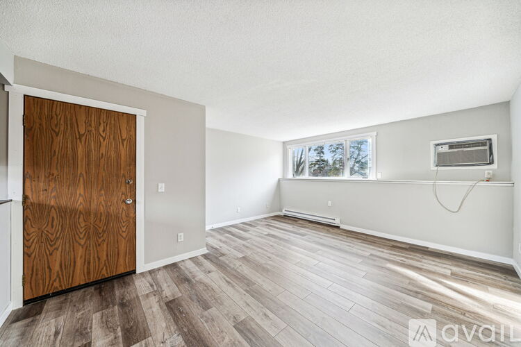 A room with a wooden door and a window with a view of trees outside.