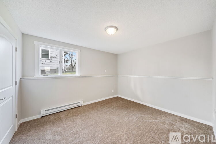 A room with a window and a carpeted floor.