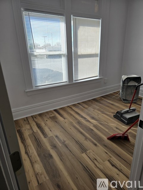 A room with wooden flooring and a window with blinds.