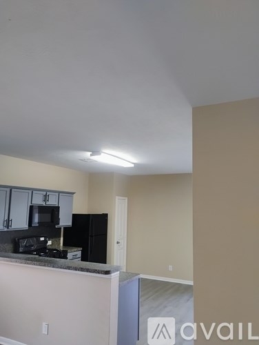 A kitchen with a black refrigerator and cabinets.