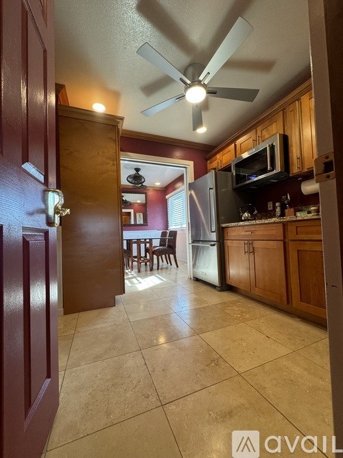 A kitchen with a fan and a refrigerator.