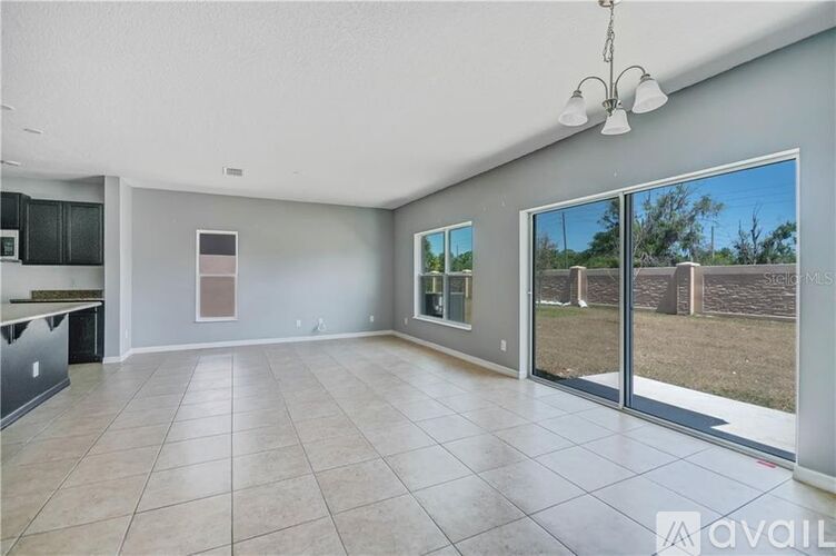 A spacious living room with a kitchen area and sliding glass doors.