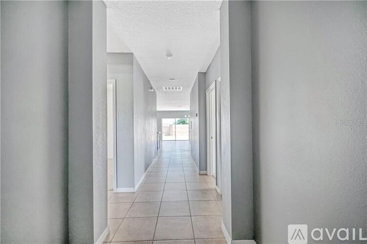 A long hallway with white walls and tile flooring.