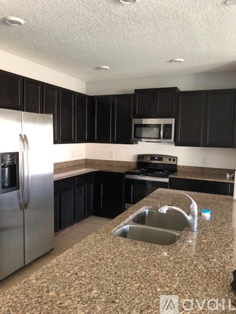 A kitchen with black cabinets and granite countertops.