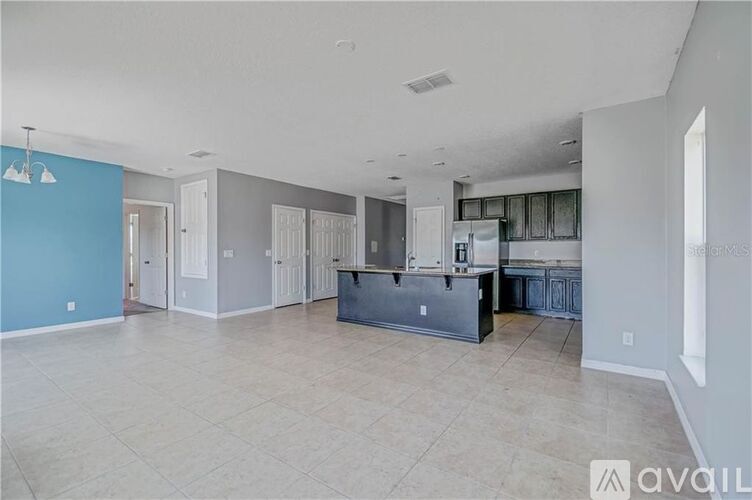 A spacious kitchen with a refrigerator, cabinets, and a countertop.