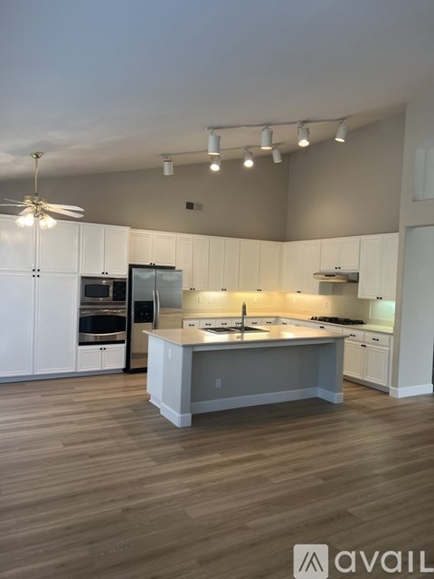 A kitchen with white cabinets and a wooden floor.