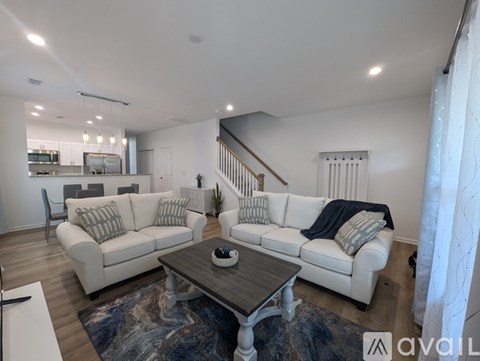 A living room with white furniture and a wooden coffee table.