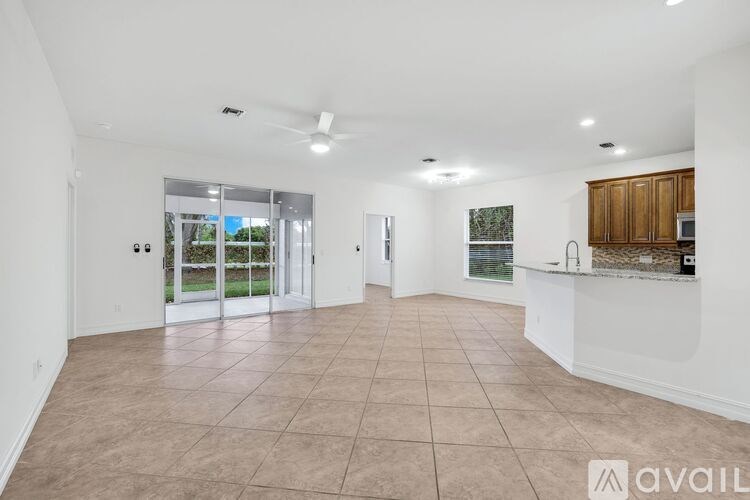 A spacious living room with a kitchen area in the background.