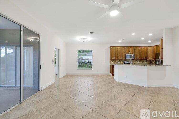 A spacious living room with a ceiling fan and sliding glass doors.
