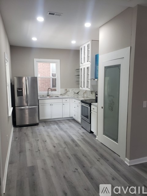 A kitchen with a refrigerator, sink, and cabinets.