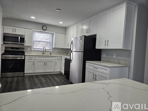 A kitchen with white cabinets and a black refrigerator.