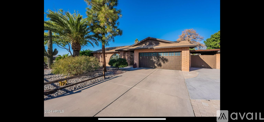 A house with a driveway and palm trees in front.
