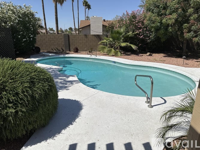 A small pool surrounded by a concrete patio and a fence.