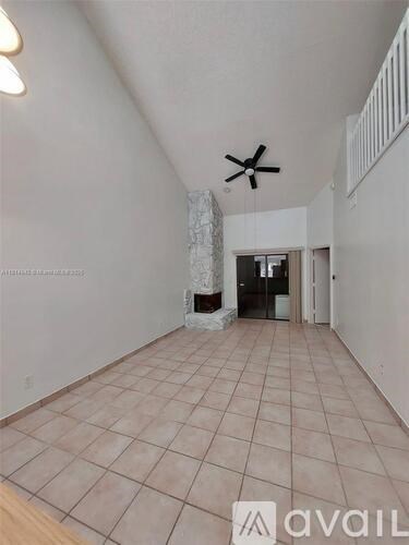 A spacious room with a ceiling fan and tiled flooring.