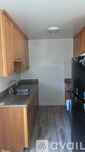 A kitchen with wooden cabinets and a black fridge.