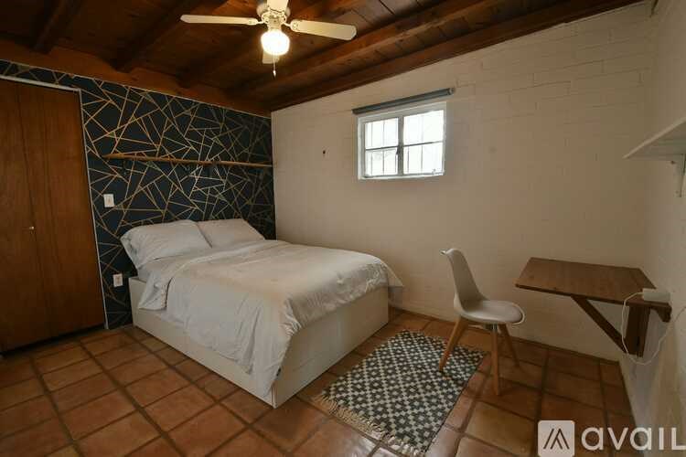 A bedroom with a bed, chair, and a window.