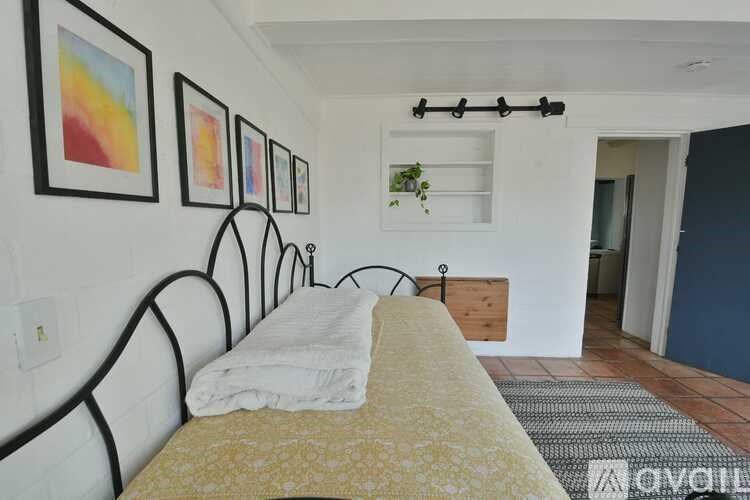 A bedroom with a bed, wall art, and a shelf.