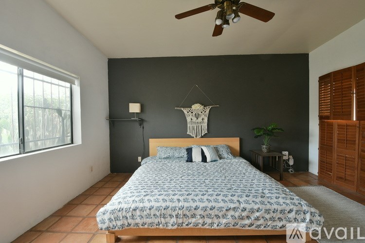 A bedroom with a bed, a ceiling fan, and a window with blinds.