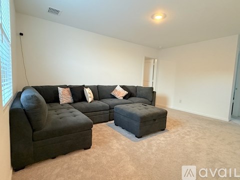 A living room with a black couch and ottoman.